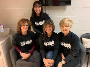 Four people posing wearing SHSM shirts
