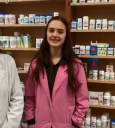 Student stands with pharmacist in front of shelves of medications
